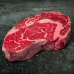 Marmoriertes US Ribeye Steak von Creekstone Farms, präsentiert auf einer Schieferplatte für Gezer Gastro-Kunden.