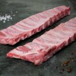 Rohe Spareribs vom Duroc-Schwein auf einer schwarzen Schieferplatte für Gezer Gastronomie-Kunden.