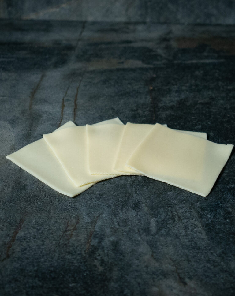 Junger Gouda in Scheiben für Gezer Gastronomie-Kunden, präsentiert auf Schieferplatte.