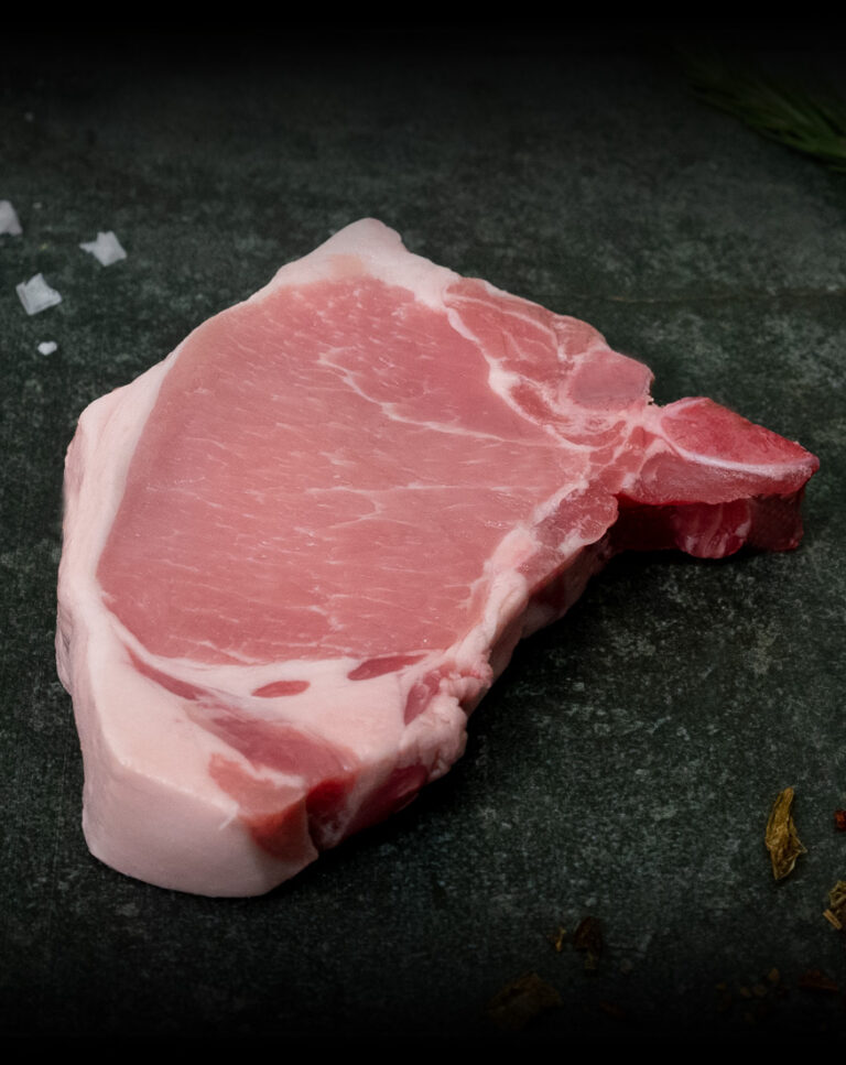 Schweinekotelett vom Strohschwein, fachgerecht pariert mit Knochen auf Schiefer präsentiert für Gezer Gastronomie-Kunden.