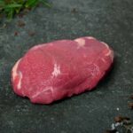 Frische Lammhüfte mit weißem Fettdeckel, präsentiert auf einer Schieferplatte für Gastronomie-Kunden von Gezer.