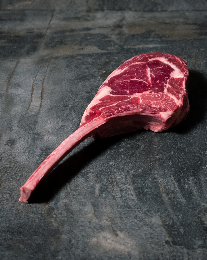 Tomahawk Steak Färse Pommern, fachgerecht pariert mit langem Knochen auf einer Schieferplatte präsentiert für Gezer Kunden.